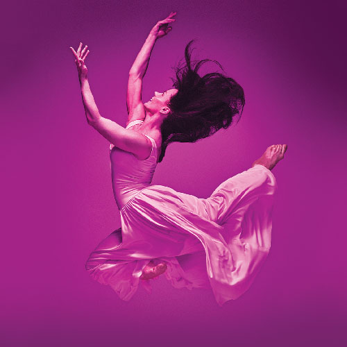 Una bailarina saltando con los brazos levantados y los pies detrás de ella