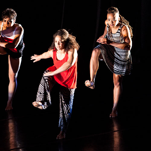 Four dancers on a stage doing an exaggerated walk step