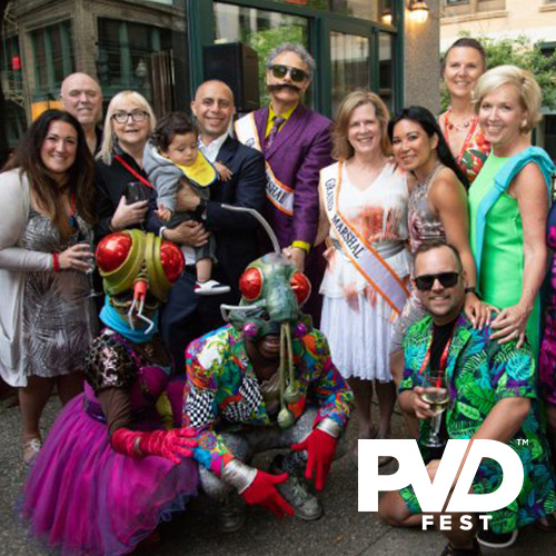 A group of colorfully dressed people and a couple of people in bug costumes posing at an outdoor party on a patio