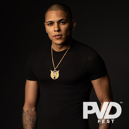 The artist Flawless posing in a black t-shirt and gold medallion necklace with the PVDFest logo overlaid in white