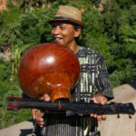 A man in a straw hat holding a gourd shaped musican instrument