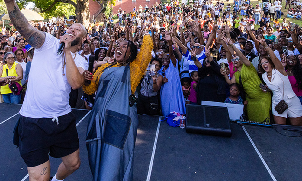 Chachi Carvalho and Elida Almeida take a selfie with their audience in a park outdoors in summer