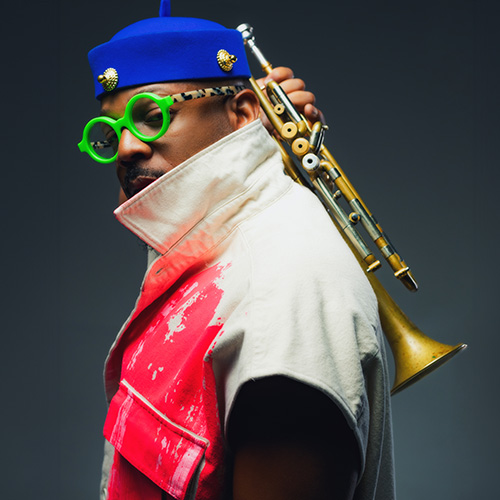 A Black man wearing a blue beret, round green glasses and a white, red and black jacket, shown in three-quarter profile holding a trumpet vertically behind his head with his right hand