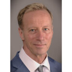 Steven Boudreau, a white man with blond hair wearing a blue blazer and white collared shirt